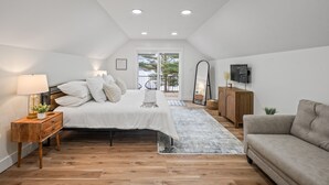 Une chambre à coucher comprenant un lit, une table de chevet, une lampe et une vue sur l’extérieur grâce à une porte coulissante.
