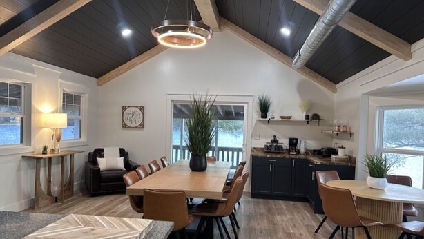 Une cuisine spacieuse dotée d’un grand îlot central, de poutres apparentes en bois et offrant une vue sur l’extérieur.