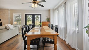 A dining area with a wooden table, black chairs, a ceiling fan, and a view through a glass door to the outdoors.
