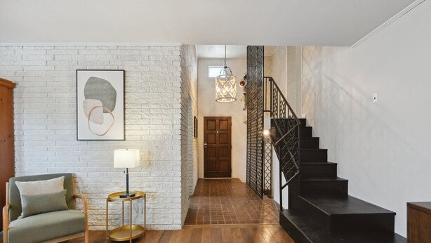 A modern interior with a staircase, a white brick wall, and a wooden floor.