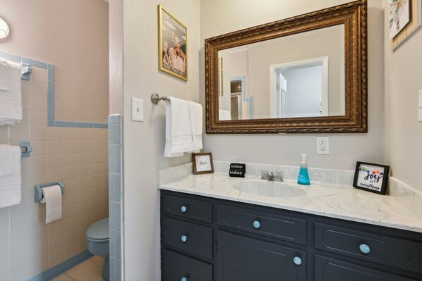 A bathroom with a large mirror, dark cabinets, a sink, and a toilet.