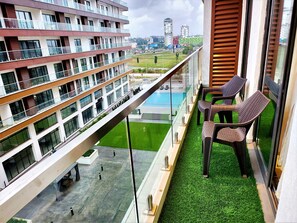 Enjoy breathtaking views of the city from your balcony overlooking a lush green space and pool area.