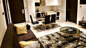 A modern living room with a dark brown sofa, a glass coffee table, and a patterned rug.