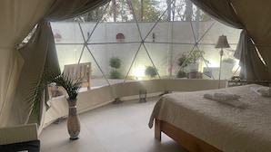 A tented room with a bed, a potted plant, and a view of the outside. - Amaj Eco Lodge (Sámara)