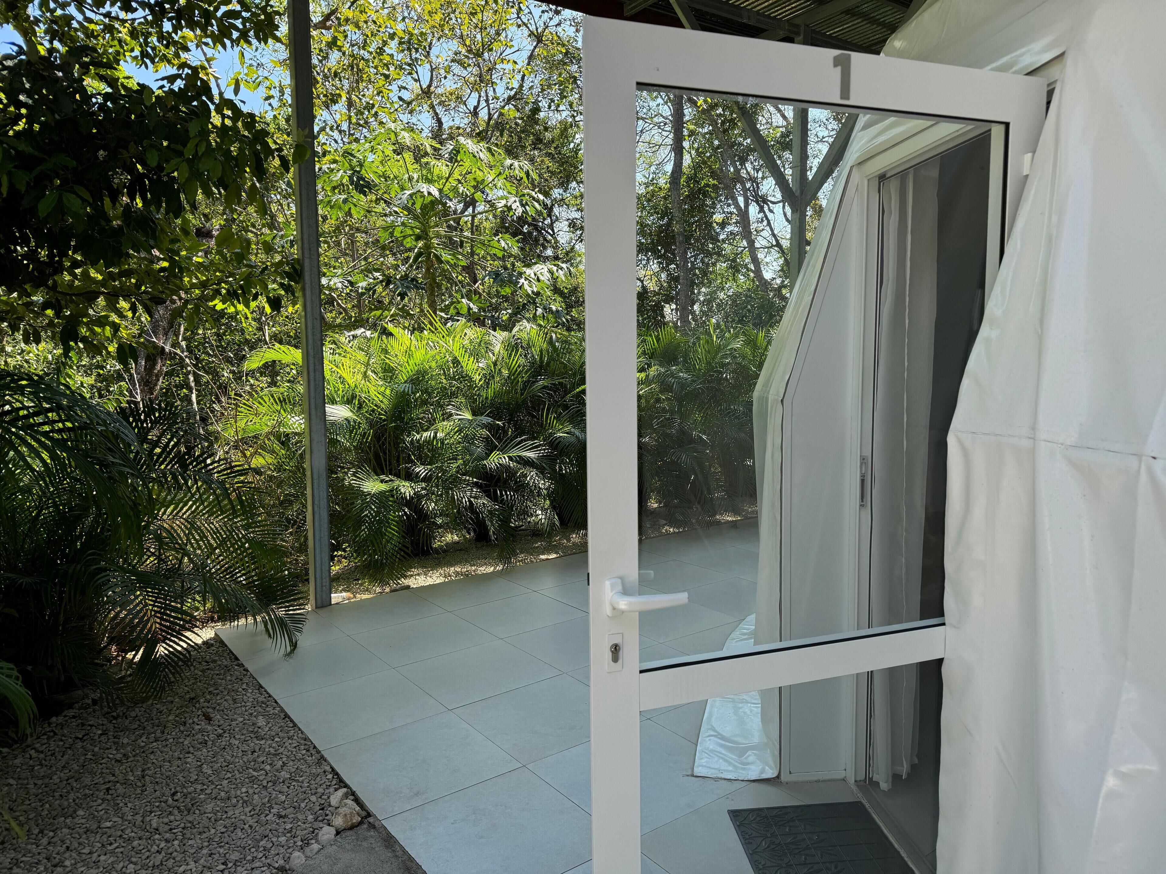 A glass door leading to a patio with a gravel path and lush greenery.