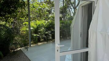 A glass door leading to a patio with a gravel path and lush greenery.