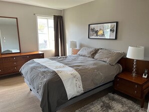A bedroom with a bed, bedside tables, a dresser, a mirror, a window with curtains, and a framed picture on the wall. - 🌟 Welcome to your dream home! 🌟 (Sainte-Anne-de-Bellevue)