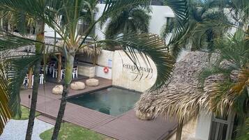Un área de piscina con palmeras, una estructura de techo de paja y un letrero que dice "empire".