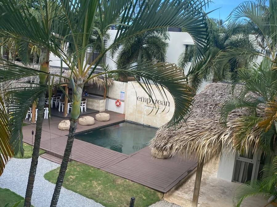 Un área de piscina con palmeras, una estructura de techo de paja y un letrero que dice "empire".