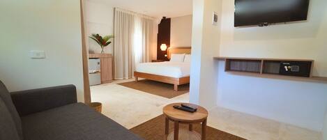 Hotelkamer met een bed, een aan de muur bevestigde televisie, een klein tafeltje met een afstandsbediening en een bank.