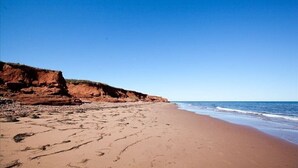 A beach with a clear sky and a rocky cliff. - Relaxing 3 bedroom cottage located in beautiful Prince Edward Island, Canada (Kensington)
