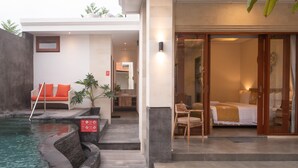 Un hotel moderno con piscina, un área de descanso con cojines anaranjados y un dormitorio con cama y vista a través de una puerta de vidrio.