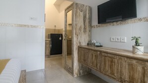 Un baño moderno con tocador de madera, televisor montado y espejo.