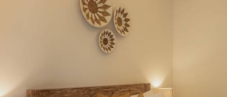 Un lit bien fait, avec une literie blanche et marron, une tête de lit en bois et des œuvres d’art décoratives accrochées au mur.