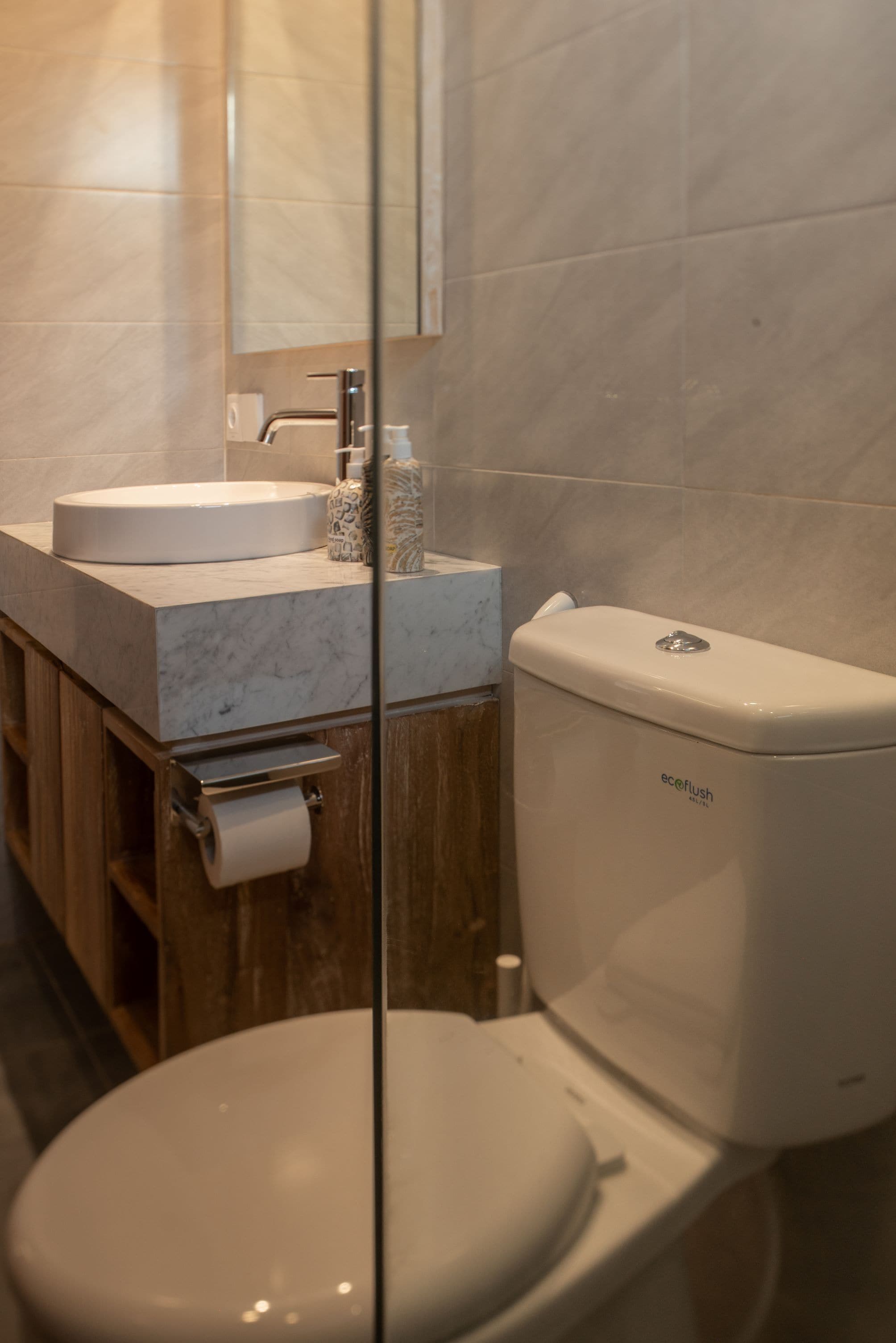 Een badkamer met toilet, wastafel en spiegel.