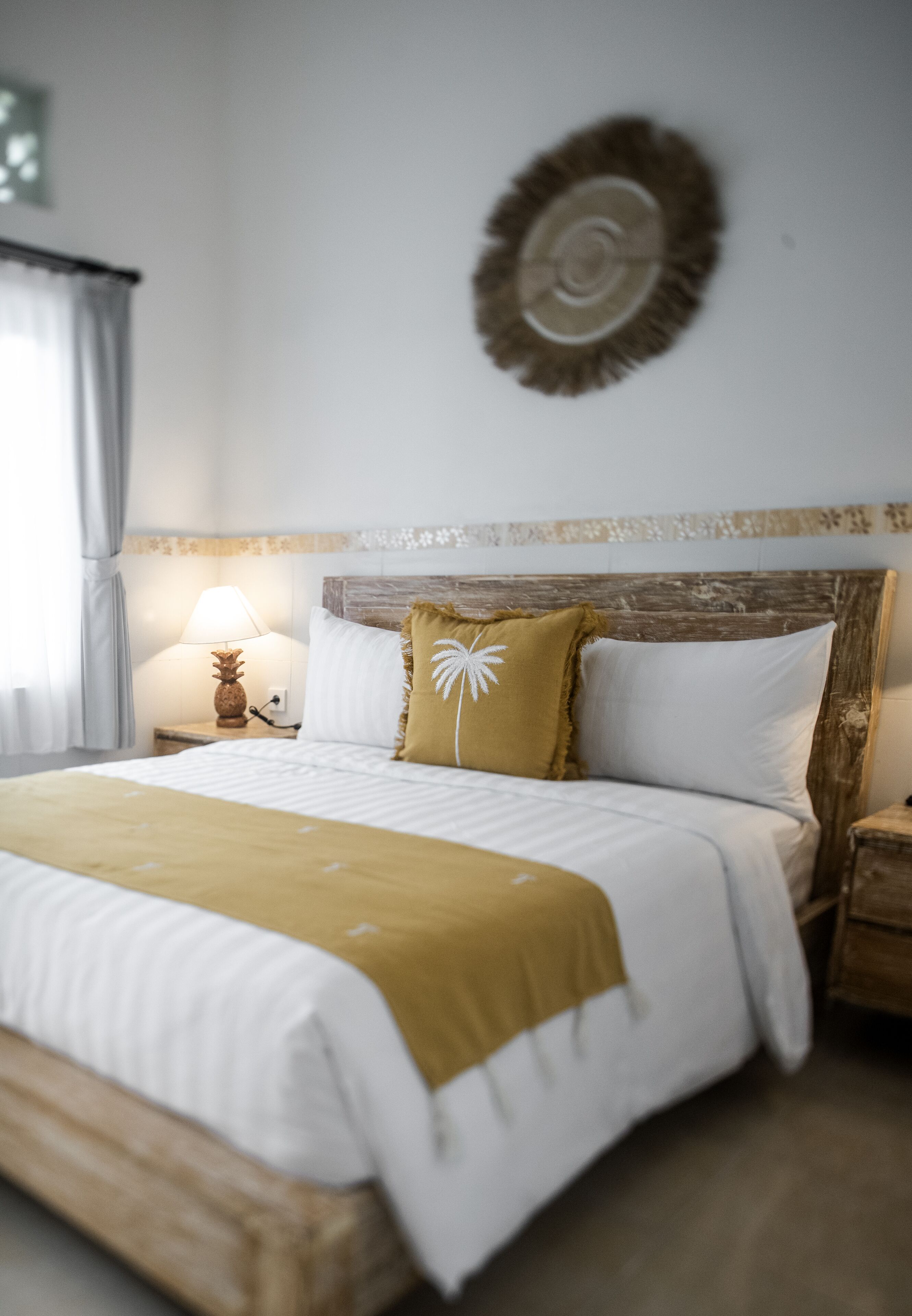 A neatly made bed with a wooden headboard, a bedside lamp, and a decorative wall piece.