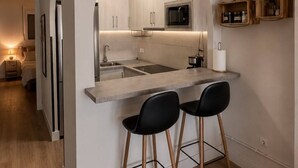 A modern kitchen with an island, bar stools, and a microwave.