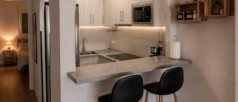 A modern kitchen with an island, bar stools, and a microwave.