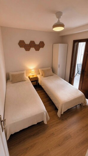 A bedroom with two single beds, a wardrobe, a ceiling fan, and a wooden floor. - EL paraiso  (Torrevieja)