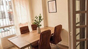 A room with a wooden dining table, four chairs, a ceiling fan, and a window with curtains.