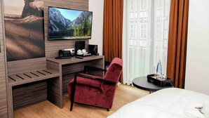 Een hotelkamer met een bed, een bureau met een computer, een televisie en een stoel.