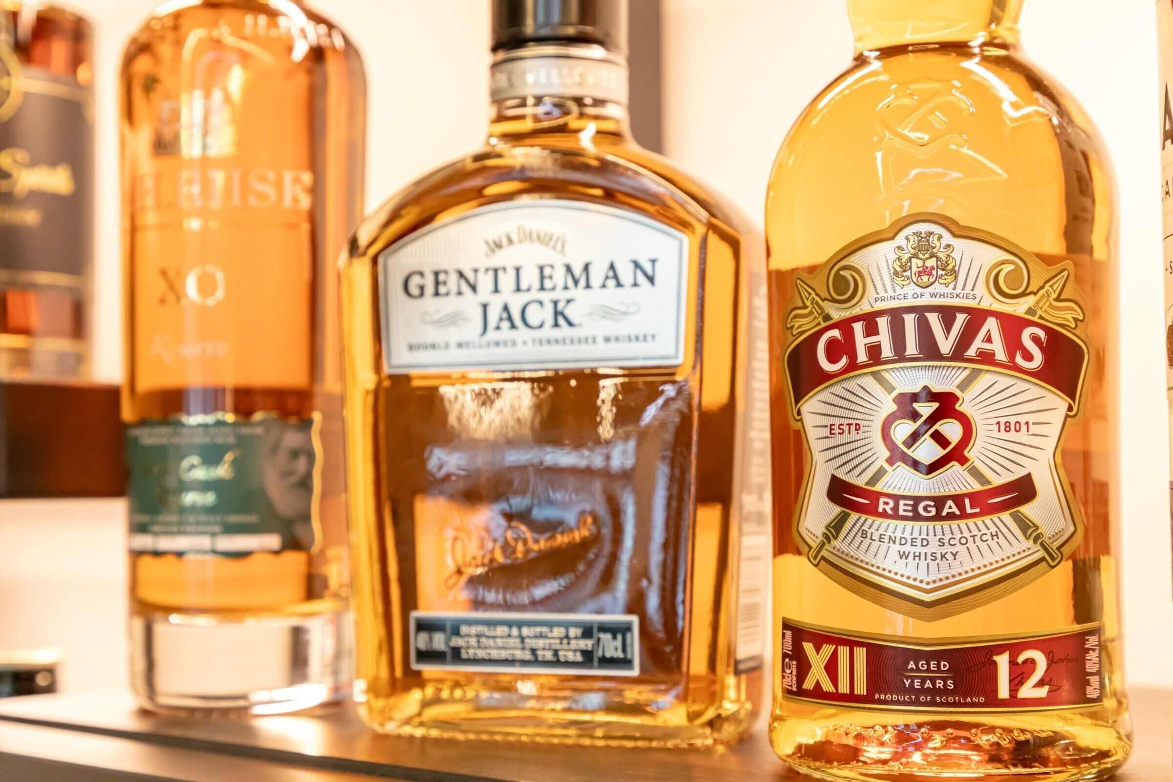 Trois bouteilles de whisky sur une étagère.