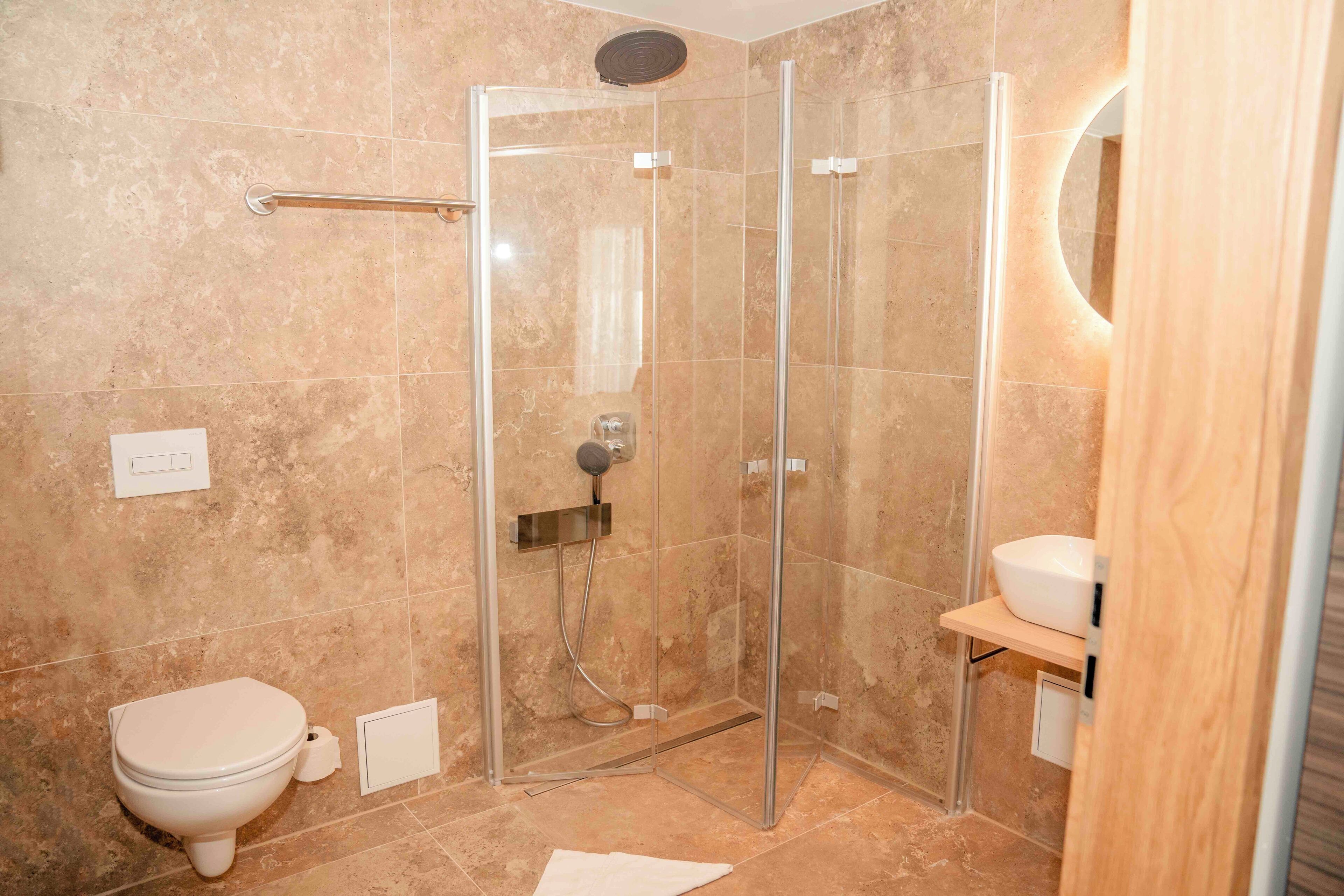 Une salle de bain avec une douche à parois de verre, des toilettes et un lavabo avec un miroir.