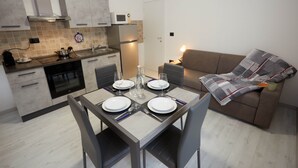 Una cuina moderna amb zona de menjador, un sofà i una taula preparada per a quatre.