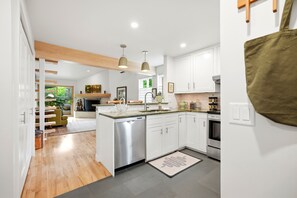 A modern kitchen with white cabinetry, a stainless steel dishwasher, and a central island with a sink.