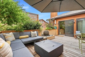 A covered outdoor seating area with a sofa, a coffee table, and a fire feature.