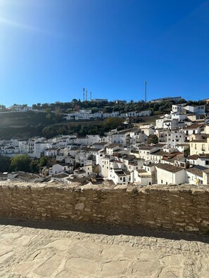 A hillside town with white buildings, a clear sky, and a rocky foreground.