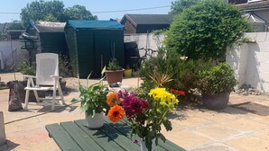A green picnic table with a vase of flowers in the center. - Cozy Coastal Apartment in Kilgetty With Views (Kilgetty)