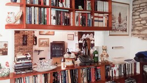 Een kamer met meerdere houten boekenplanken vol boeken, een vintage telefoon en een ingelijst foto op de muur.