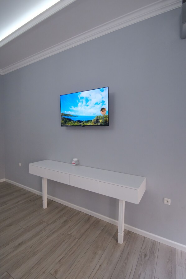 A room with a mounted TV on the wall, a white console table, and light-colored wooden flooring. - Oscar Hotel (Samarkand)