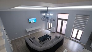 A modern living room with a sectional sofa, a coffee table, and a TV mounted on the wall. - Oscar Hotel (Samarkand)
