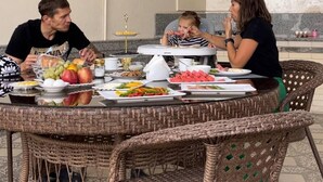 A round wicker table with a variety of food items and a white electric kettle. - Oscar Hotel (Samarkand)