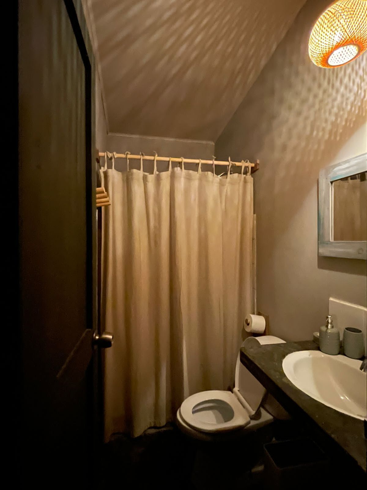 Un baño pequeño con inodoro, lavamanos y cortina de ducha.