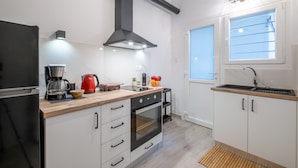 Een moderne keuken met een inbouwoven, een koffiezetapparaat en een rode waterkoker op het aanrecht.