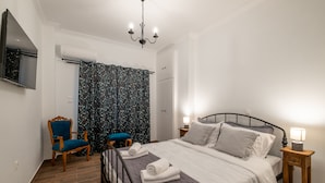 Een slaapkamer met een bed, een stoel, een nachtkastje, een televisie en een douche.