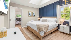 Une chambre à coucher avec un lit, une table de chevet, une lampe et une vue sur l’extérieur.