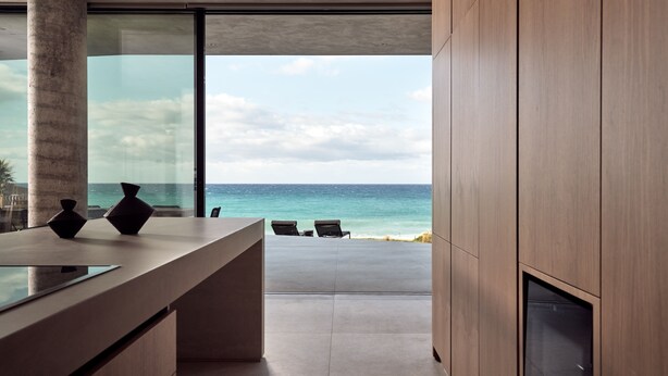 Een modern interieur met een groot raam met uitzicht op de oceaan, een minimalistisch receptiebalie en enkele stoelen.
