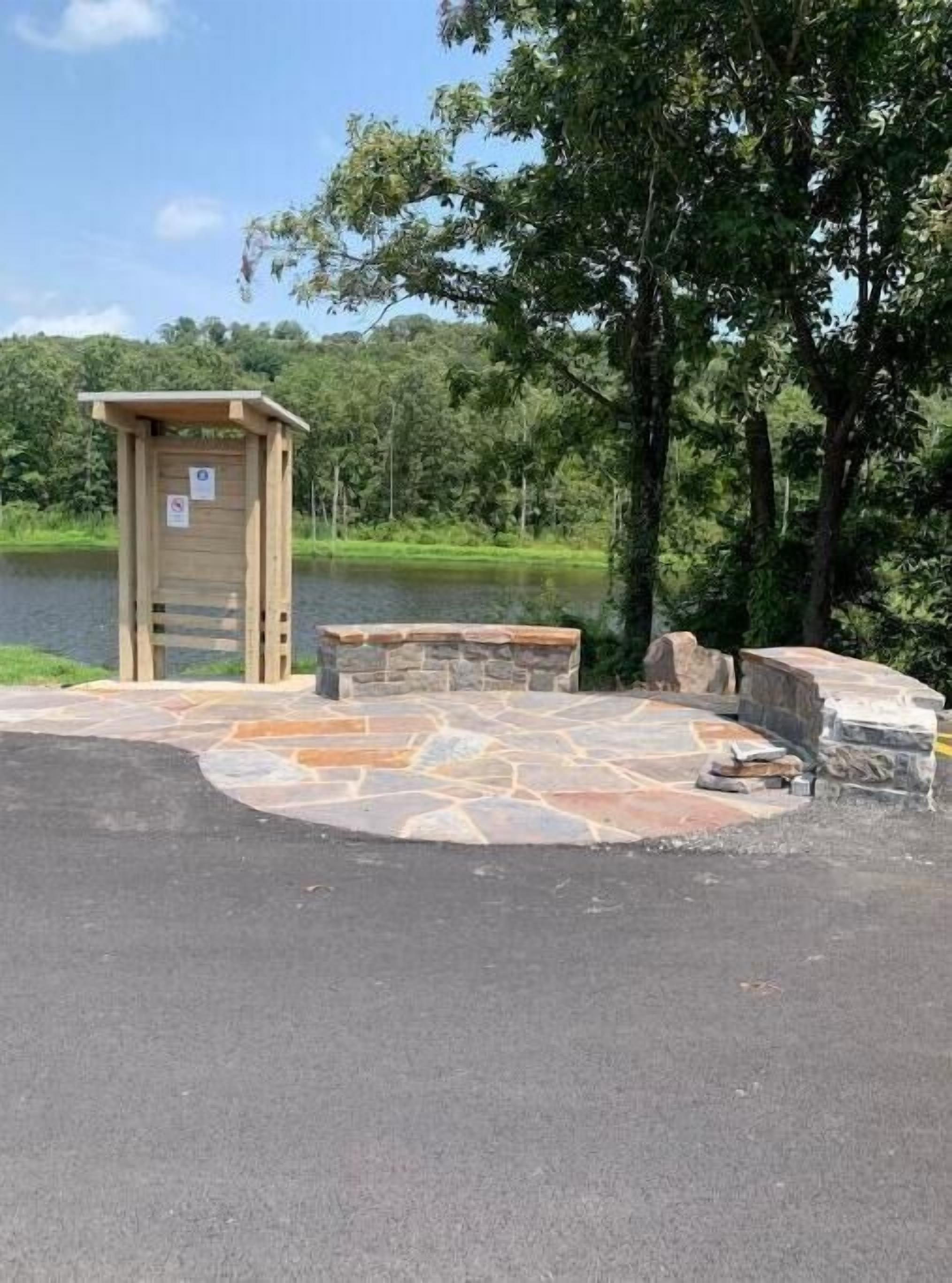 A wooden structure with a door, a stone bench, and a paved area with stone tiles.