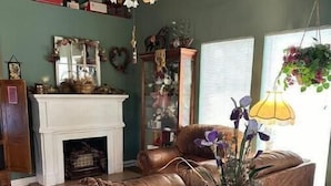A cozy living room with a fireplace, leather sofa, and a table with a vase of flowers.