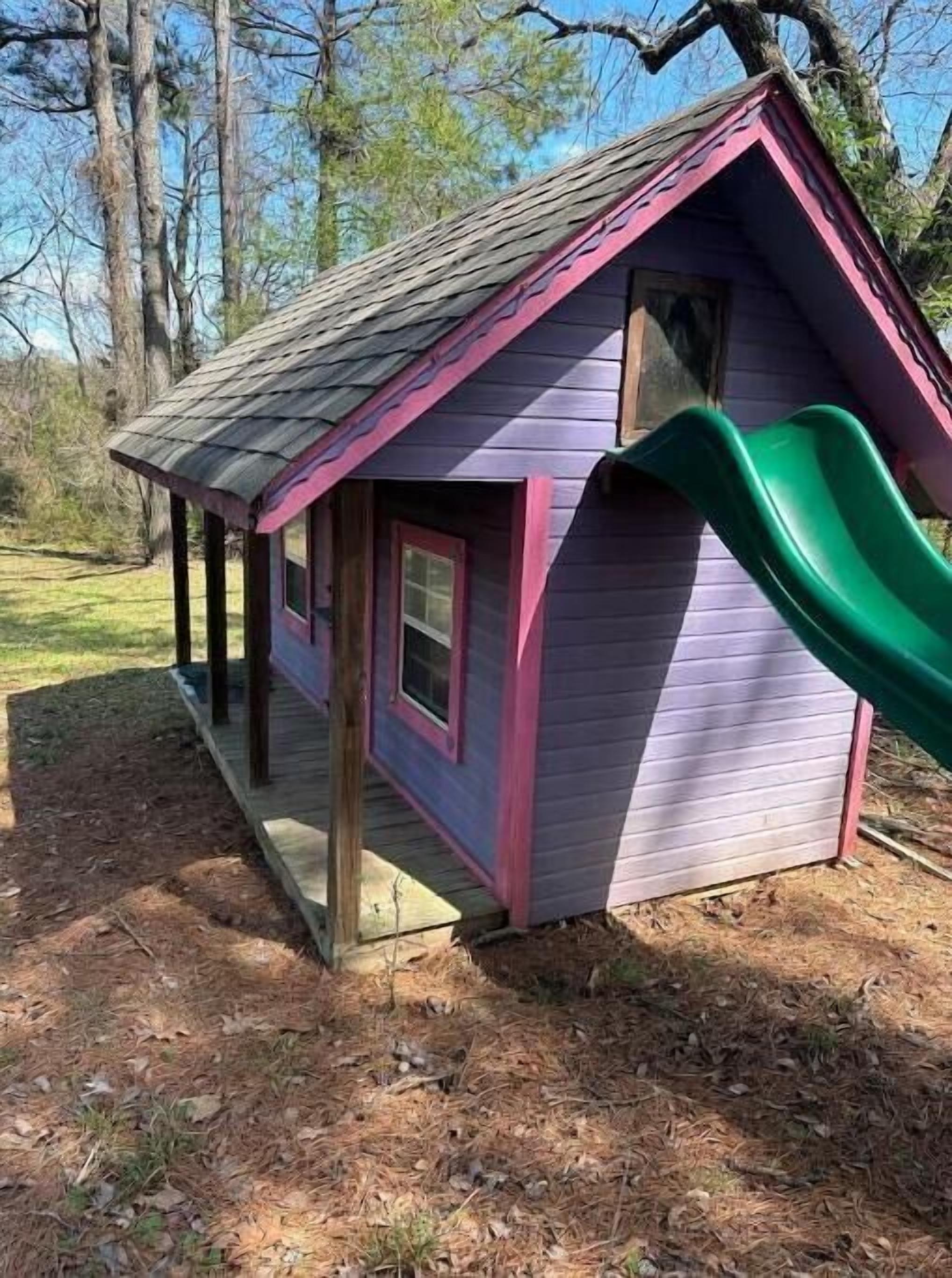A small, single-story building with a purple exterior and a green slide.