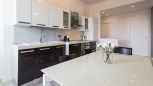 A modern kitchen with white cabinets, a black stove, and a dining table with chairs. - Ravenna Sky View Apartment (Ravenna)