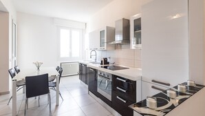 A modern kitchen with a central island, black cabinets, stainless steel appliances, and a white countertop. - Ravenna Sky View Apartment (Ravenna)