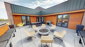 Eine Terrasse im Freien mit Feuerstelle, Sitzgelegenheiten und Grillbereich.