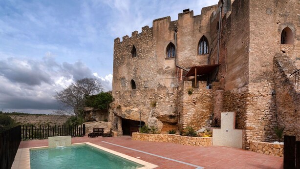 Un bâtiment en pierre doté d’une piscine, d’une terrasse en bois et offrant une vue sur une colline.