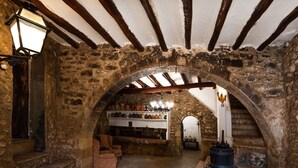 Une pièce aux murs de pierre, dotée d’une voûte, d’une cheminée et d’étagères où sont exposées des poteries.