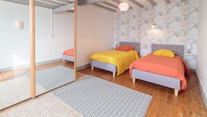 Une chambre moderne avec deux lits, un grand miroir et un papier peint à motifs.